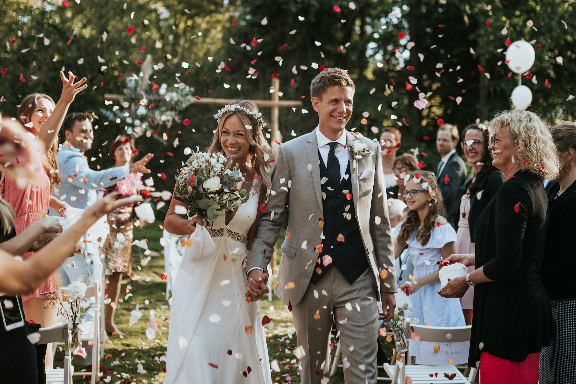 ein Brautpaar läuft lachend durch einen Konfettiregen von Blüten nach der Trauung (/images/bilder/thumbs/376_1_bild_5G1A3795_Kopie_2.jpg)