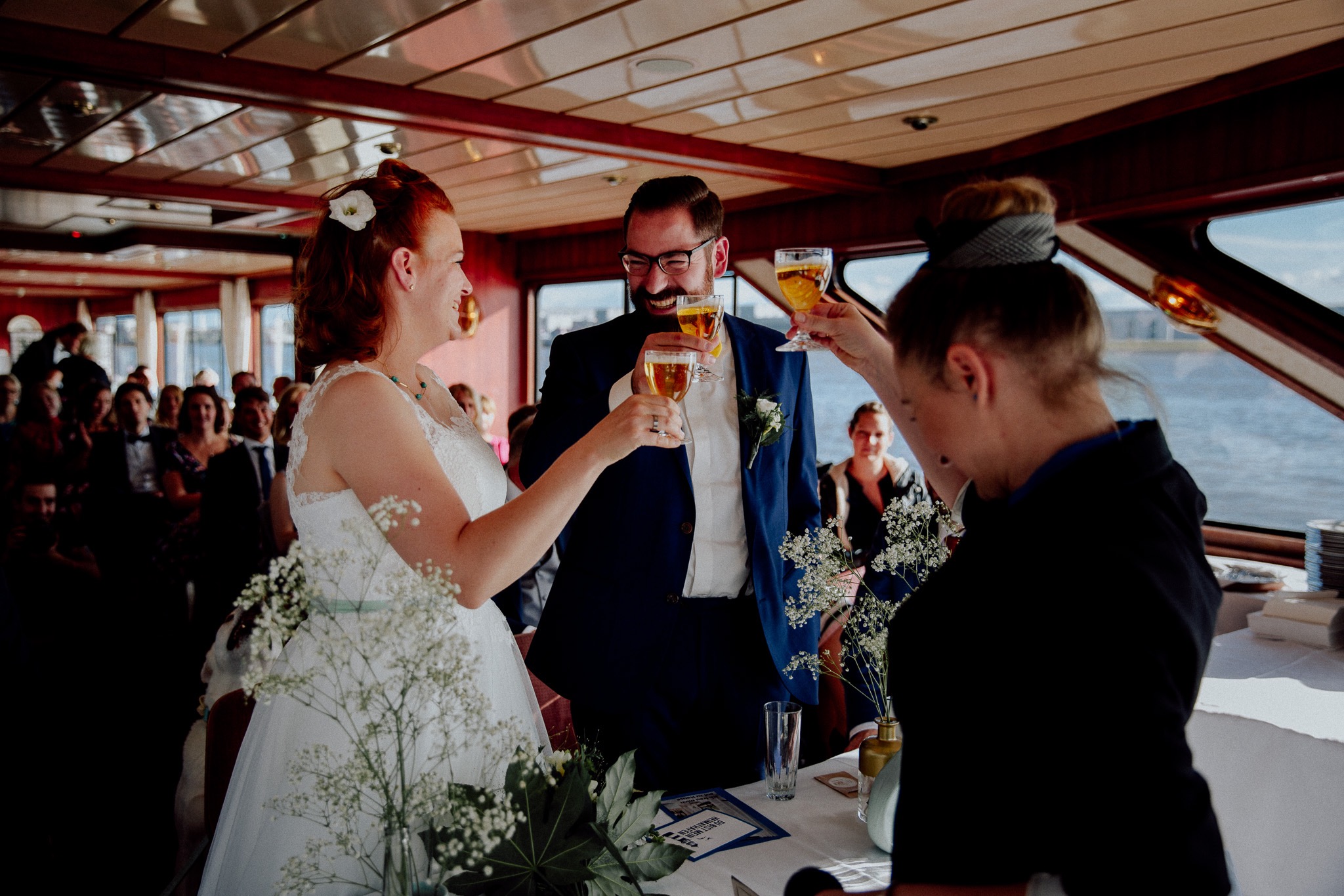 ein Brautpaar bei einer freien Trauung auf der Barkasse mit Constanze Marienfeld. Alle stossen lachend mit einem kleinen Glas Bier an. (/images/bilder/thumbs/376_6_bild_WSMM7009_Kopie.jpg)